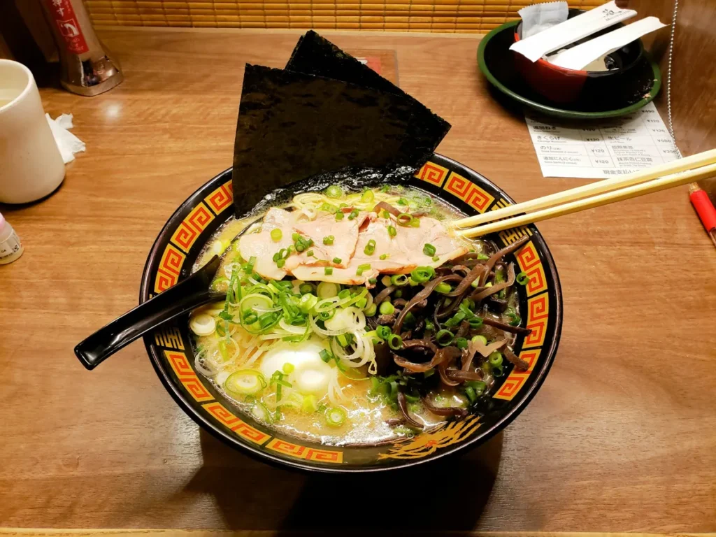 Bowl of authentic Japanese tonkotsu ramen topped with chashu pork, green onions, seaweed, and noodles in rich pork broth.